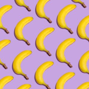 A vibrant pattern of yellow bananas arranged on a purple background creating a striking visual effect.