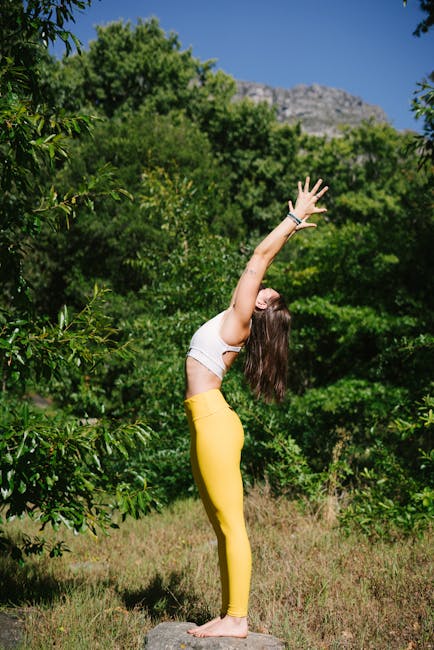 pexels-photo-3820430-3820430 A woman in yellow leggings performs a yoga pose outdoors surrounded by green trees.