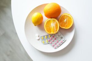 A plate of fresh citrus fruits and blister packs of pills, highlighting nutrition and healthcare.