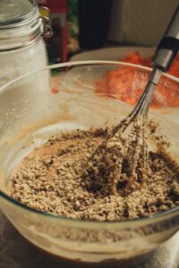 A close-up of dessert preparation with a whisk in a mixing bowl, showcasing textured ingredients.