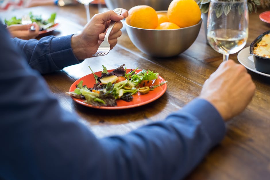 Casual dining scene with a fresh salad and white wine on a wooden table setting.